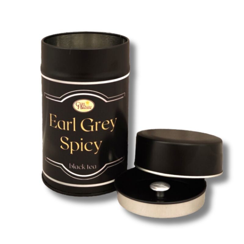 Metalowa puszka czarnej herbaty Earl Grey Spicy, obok otwarta pokrywka z sitkiem na białym tle.
